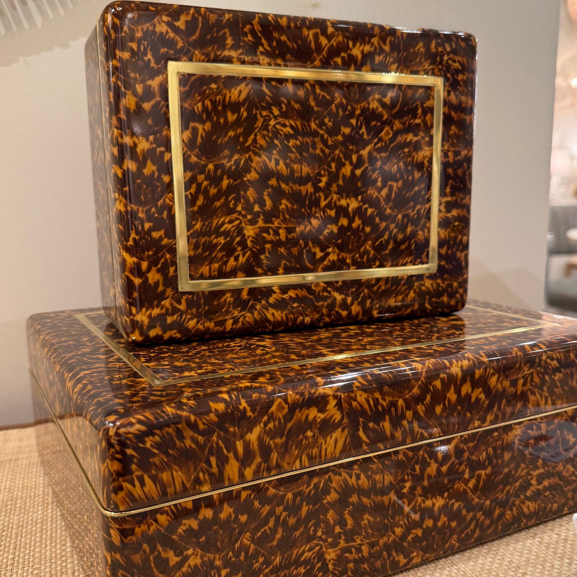 Tortoiseshell-patterned boxes with gold accents on a textured surface.