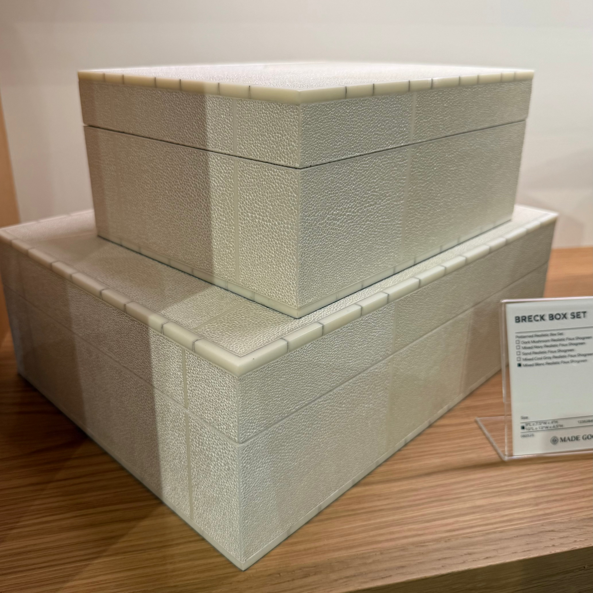 Set of 2 textured storage boxes on a wooden surface with a label in the background.