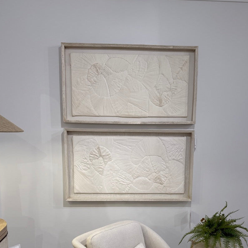 Beige armchair with cushions in a room with framed artwork on the wall.