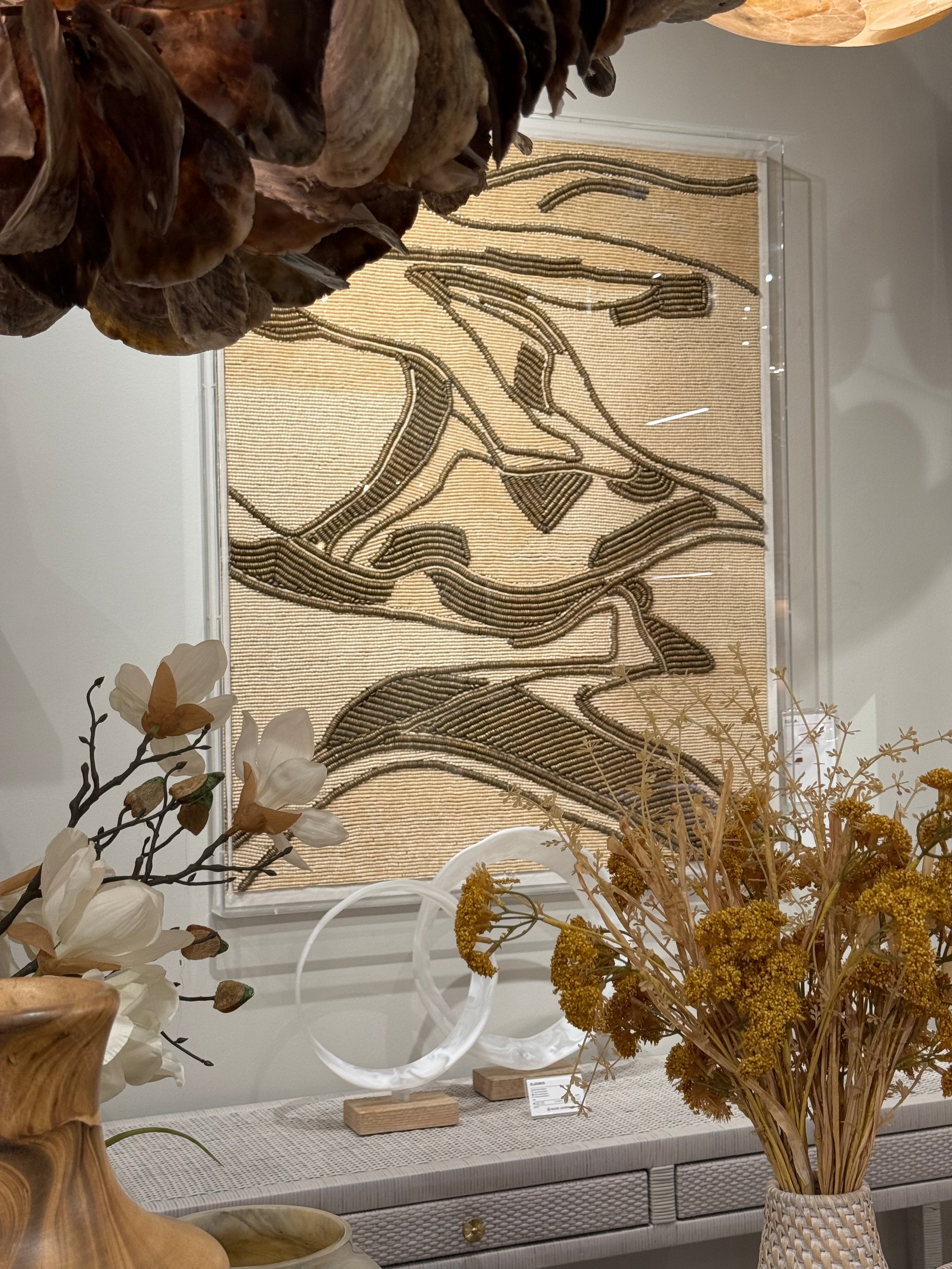 Decorative interior setting with abstract wall art, plants, and a vase.