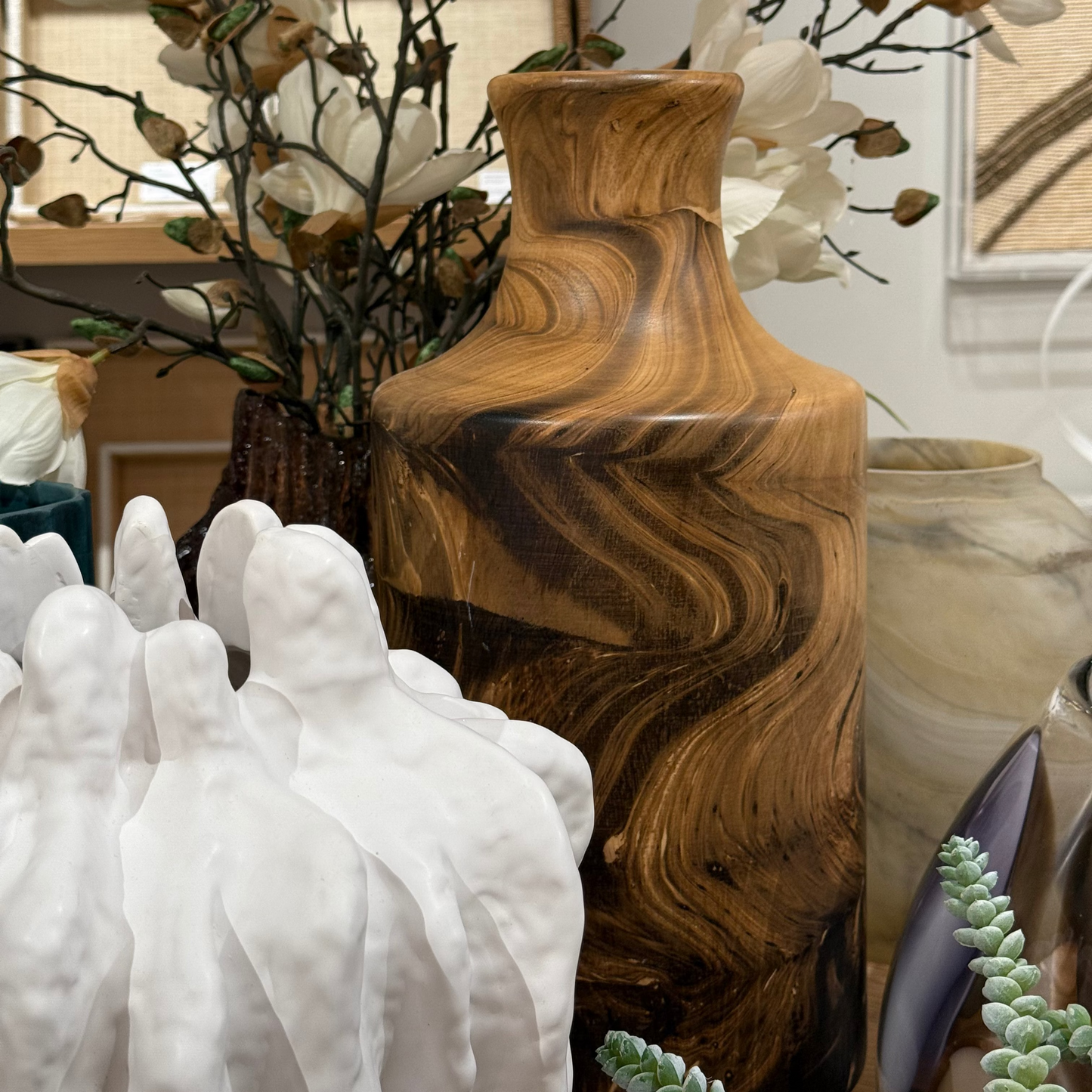 Decorative items including a wooden vase, white sculptures, and floral arrangements.