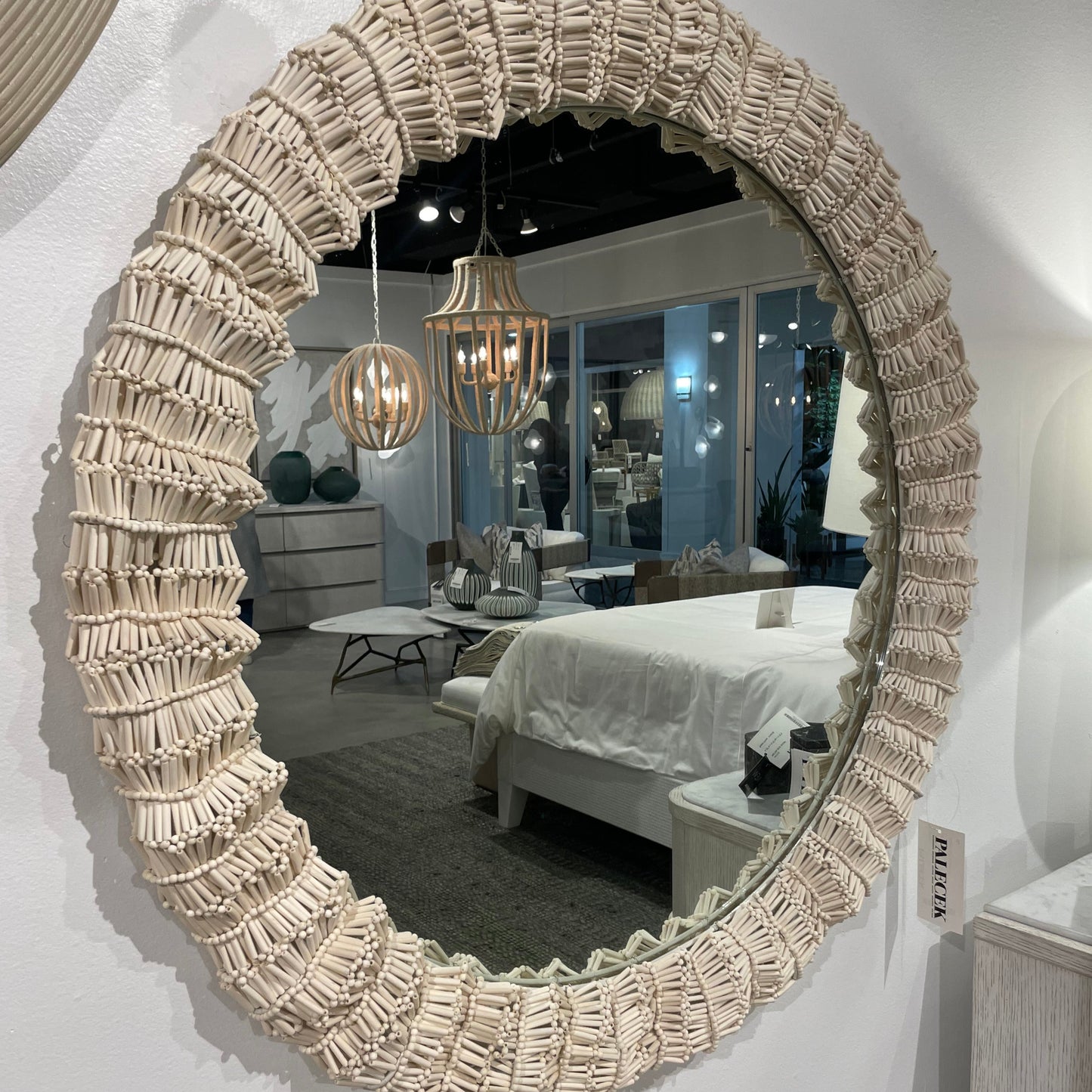 Round mirror with decorative beige frame on a white wall