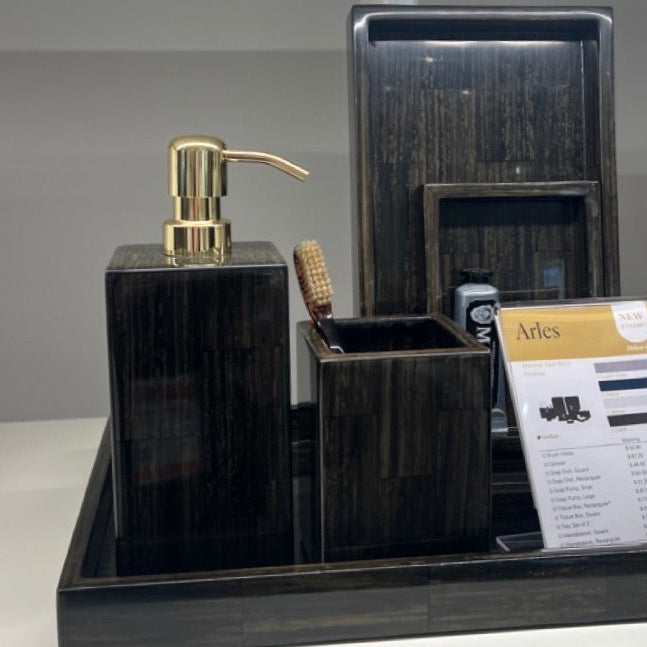 Bathroom vanity set with black marble tray, gold pump, and other accessories on a white counter.