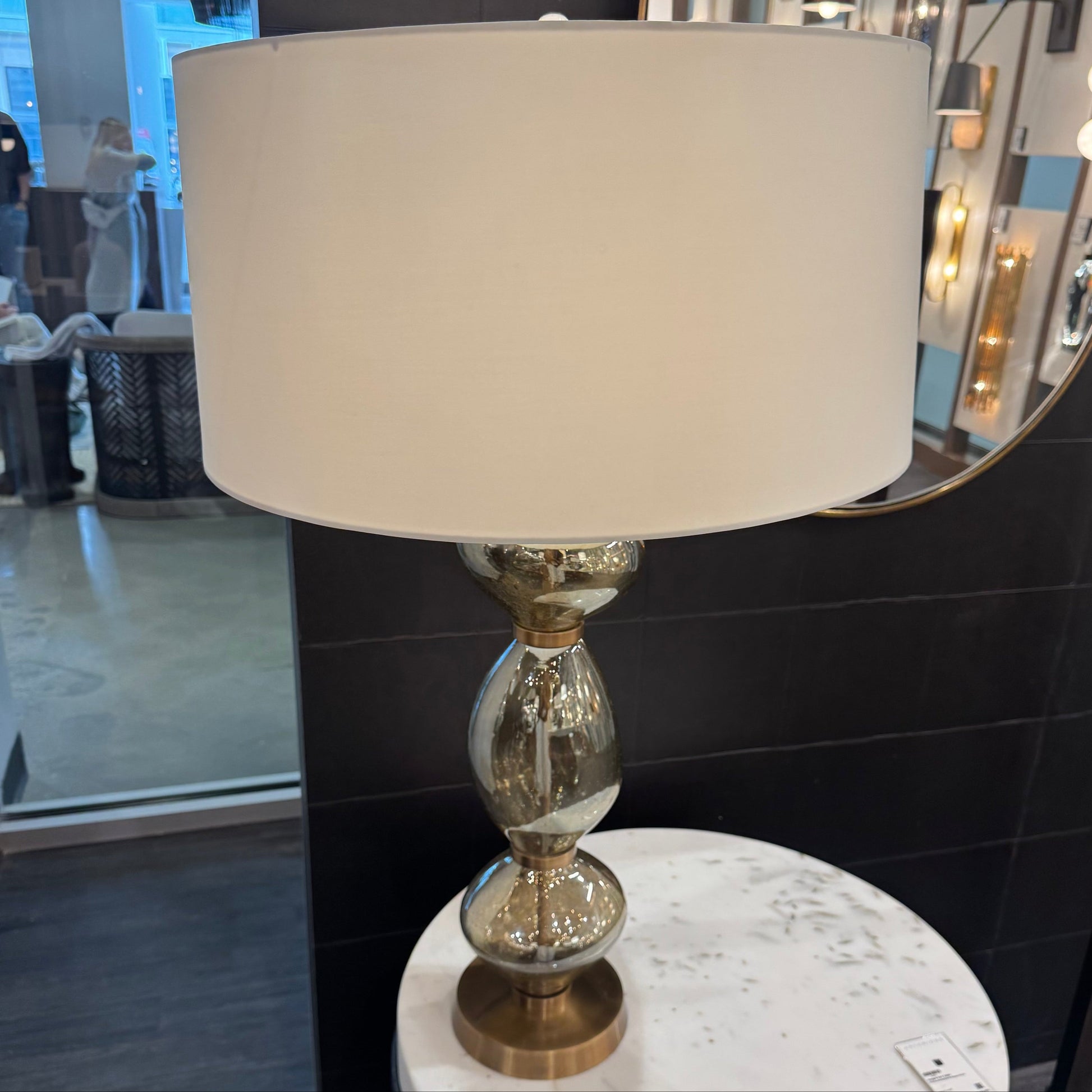 Table lamp with a beige shade and decorative base on a round marble table.