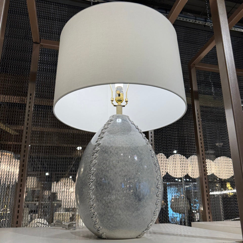 Decorative lamp with textured base and white shade in a showroom setting
