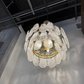 Modern chandelier with crystal-like design in a room with exposed ceiling and concrete floor.