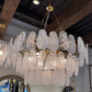 Chandelier with glass shades in a room with wooden beams and mirrors.