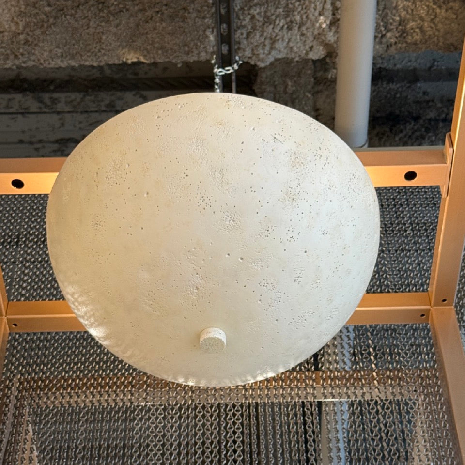 Round white ceiling light fixture on a textured wall background