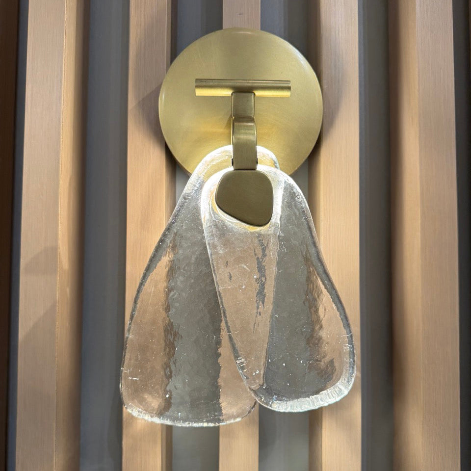 Wall-mounted light fixture with glass shade on a striped wall