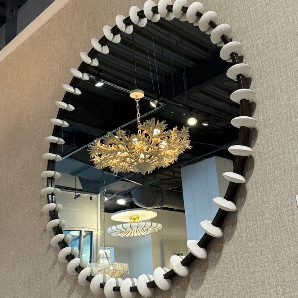 Round mirror with decorative frame on a textured wall