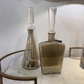 Two glass bottles on a marble surface with a white wall in the background