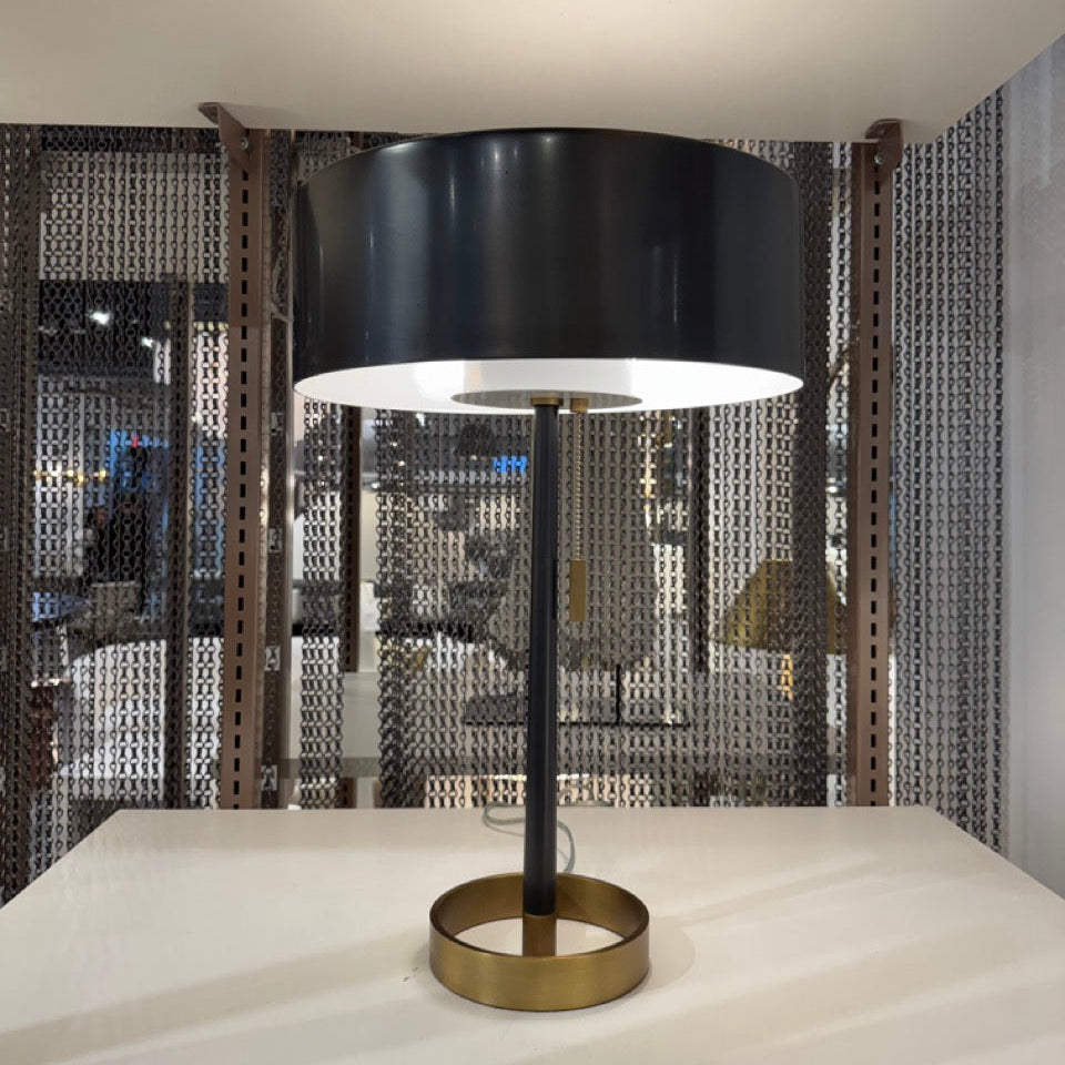 Modern table lamp with black shade and gold base on a white surface.