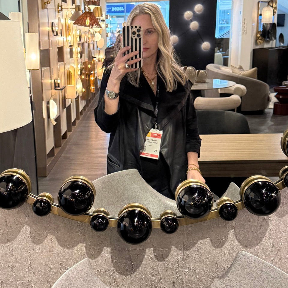 Person taking a mirror selfie in a store with decorative mirrors and furniture.
