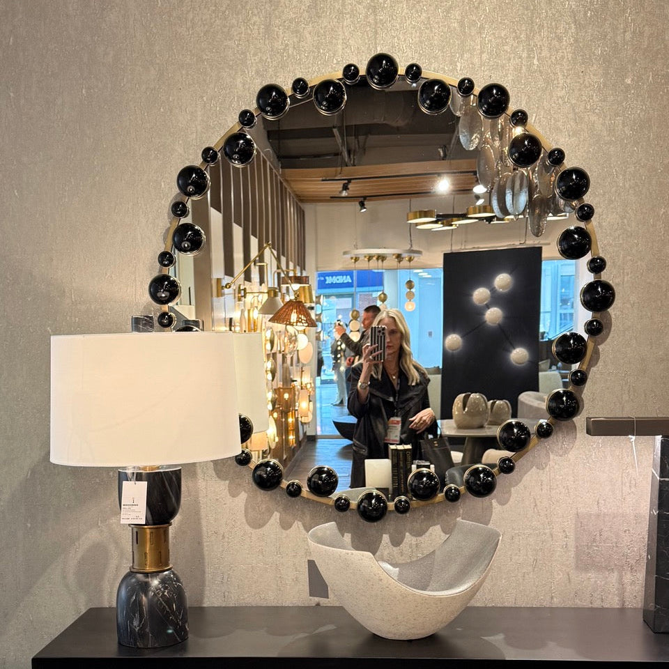 Decorative mirror with black spherical accents on a wall in an interior setting.