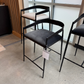 Modern black bar stools with gray seats in a showroom setting.