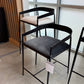 Black metal bar stools with gray cushioned seats in a showroom setting.