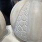 White stone sculpture with textured surface on a reflective surface