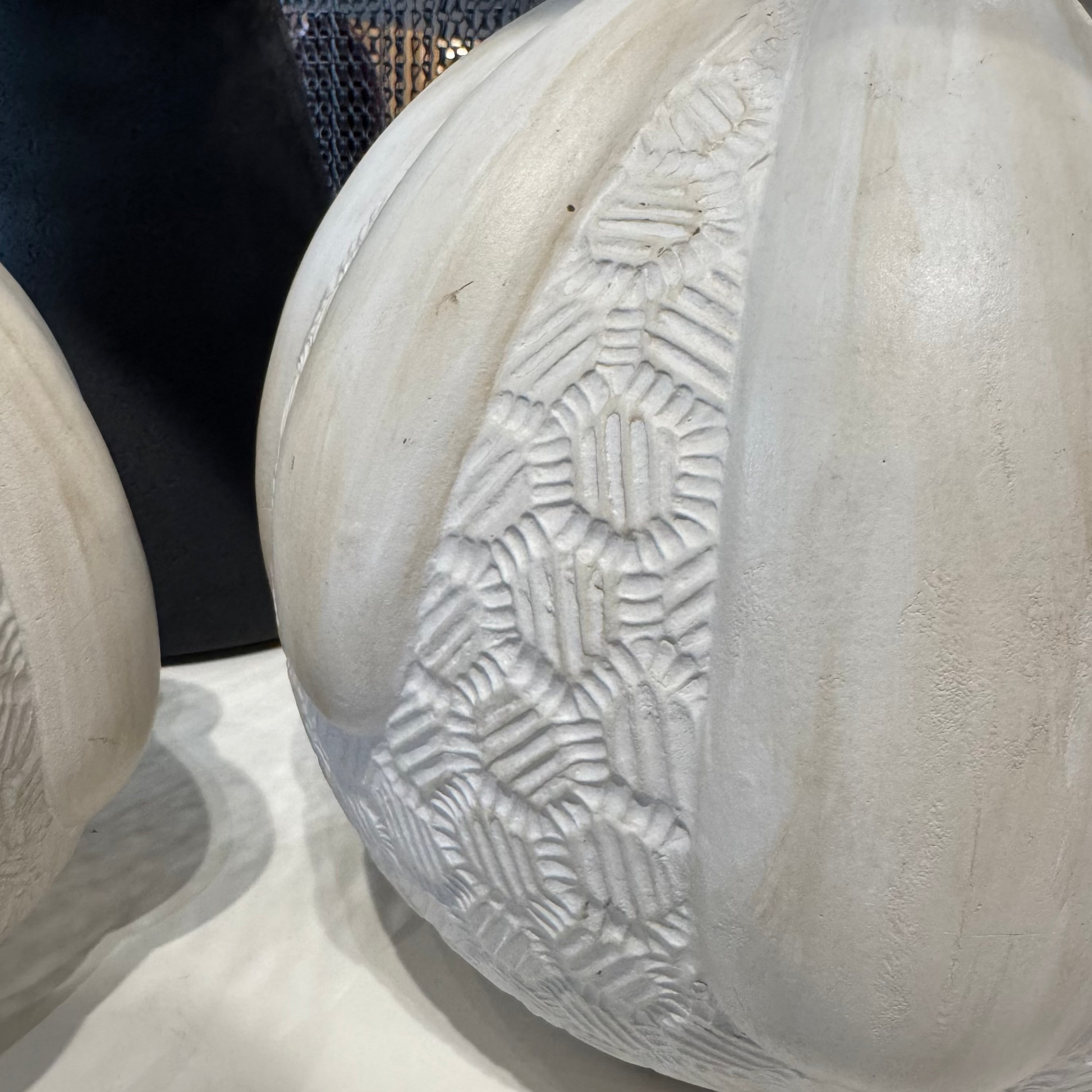 White stone sculpture with textured surface on a reflective surface