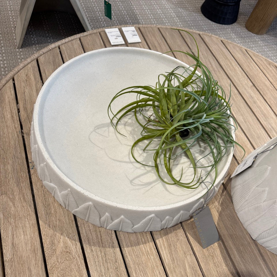 Round white table with a plant on a wooden deck