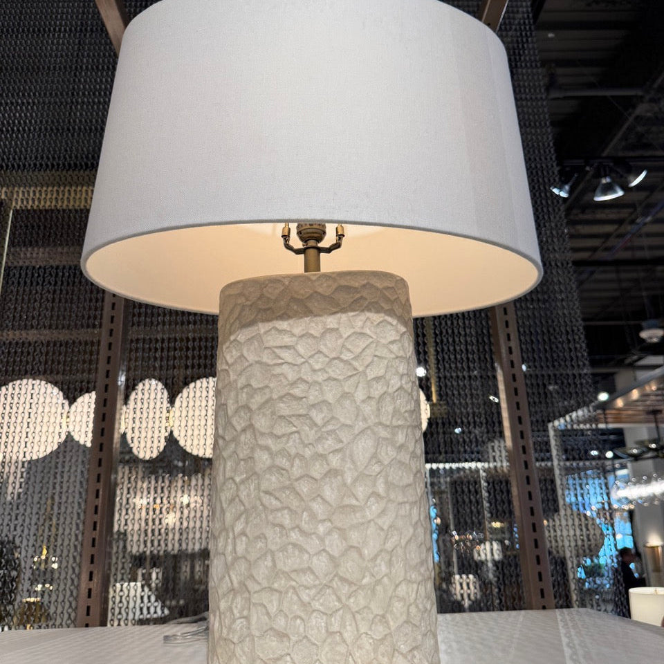 Table lamp with textured base and white shade in a modern indoor setting