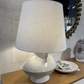 Table lamp with a textured base and beige shade on a wooden surface.