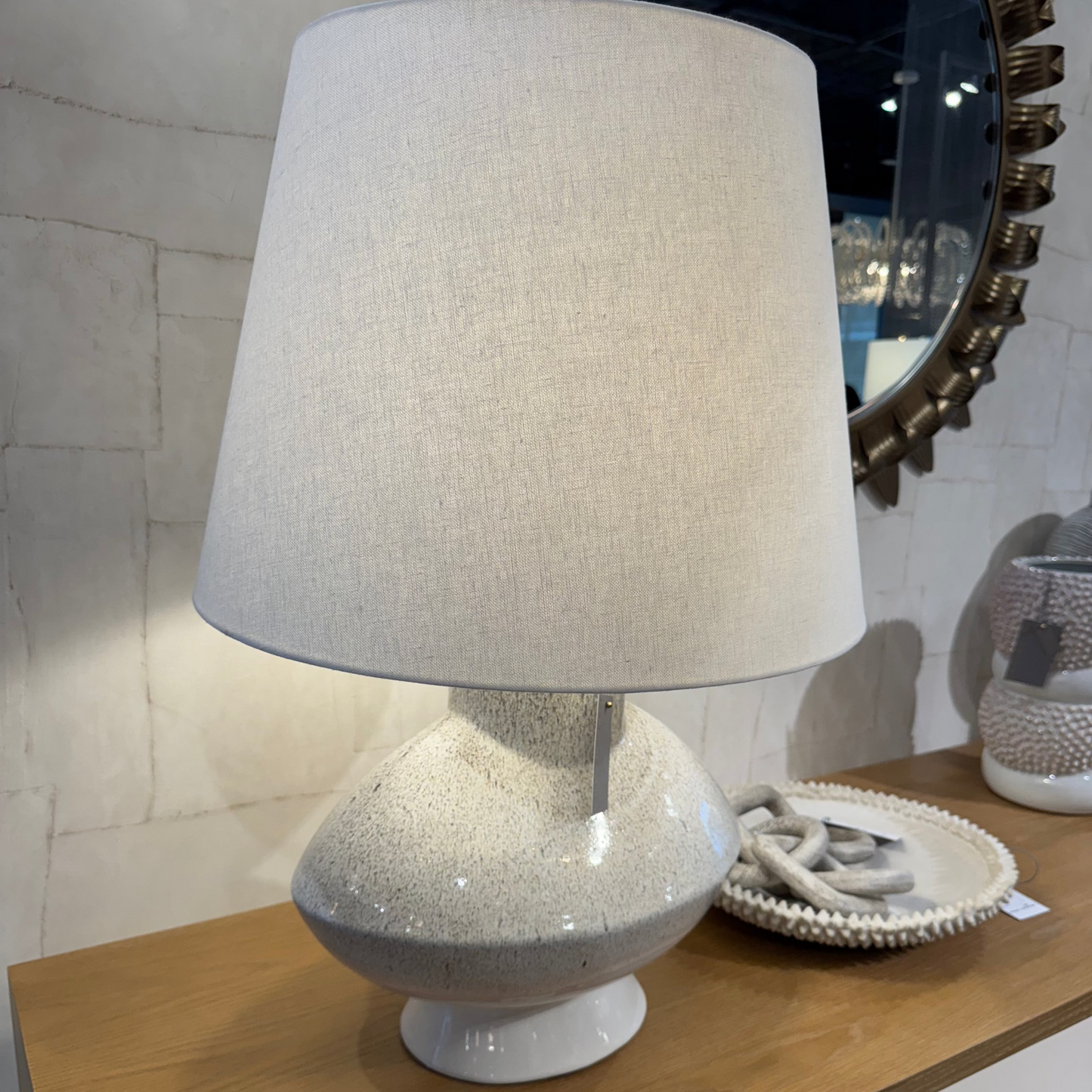 Table lamp with a textured base and beige shade on a wooden surface.