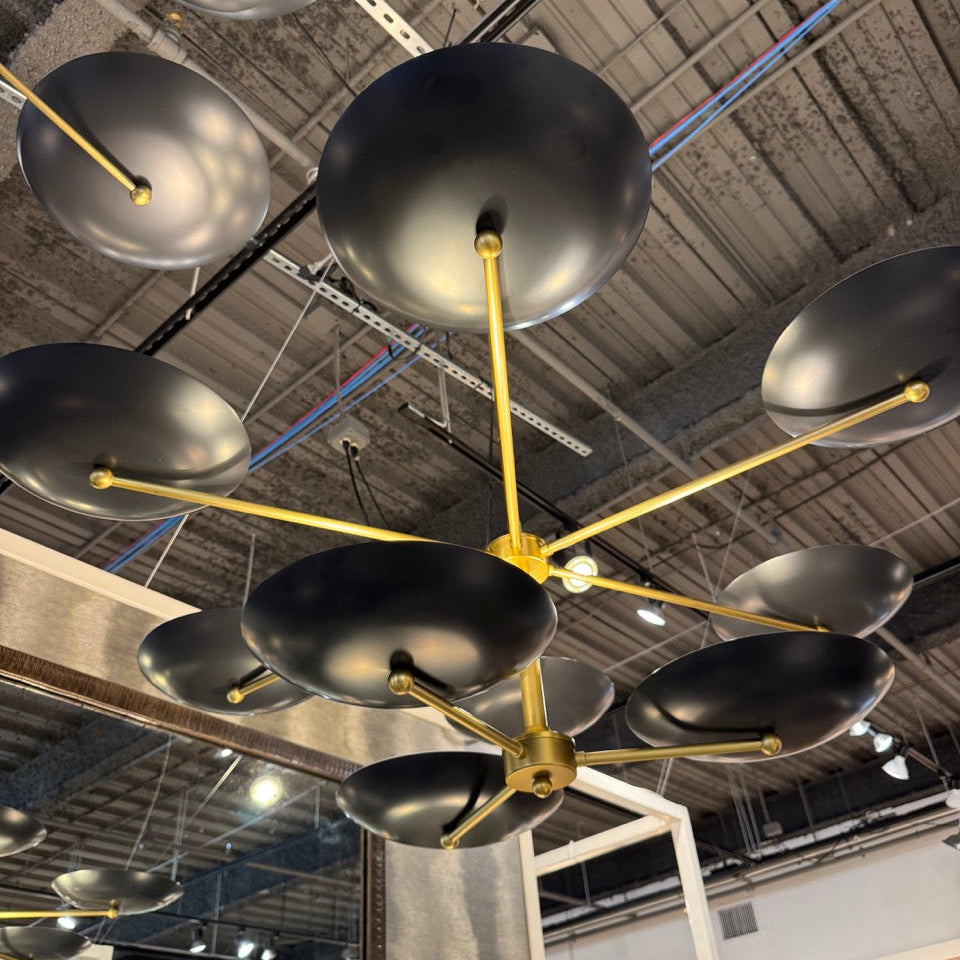 Modern chandelier with black lampshades and gold arms hanging from a ceiling.