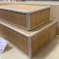 Two woven storage boxes with silver trim on a display surface.