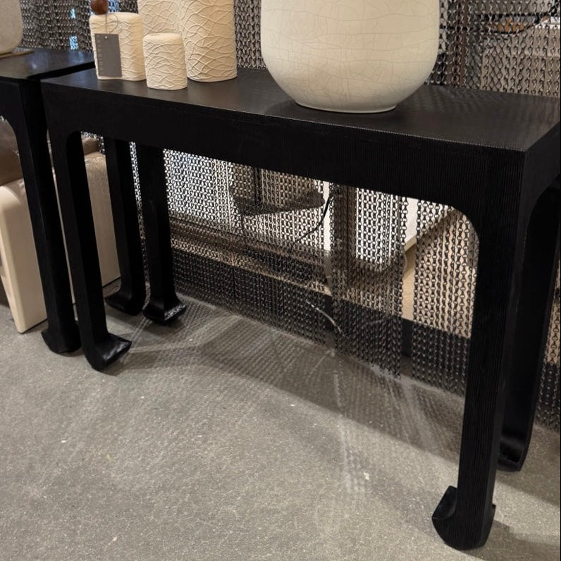 Black console table with decorative items against a textured wall.