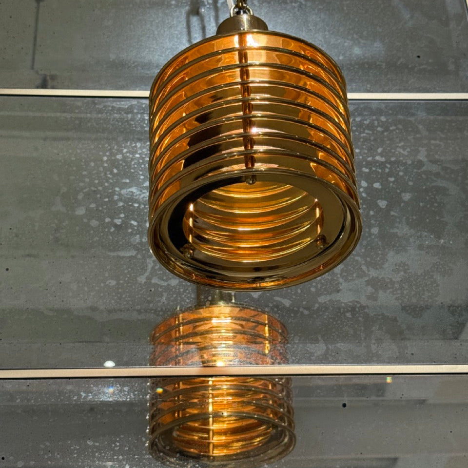 Gold metallic pendant light on a reflective surface