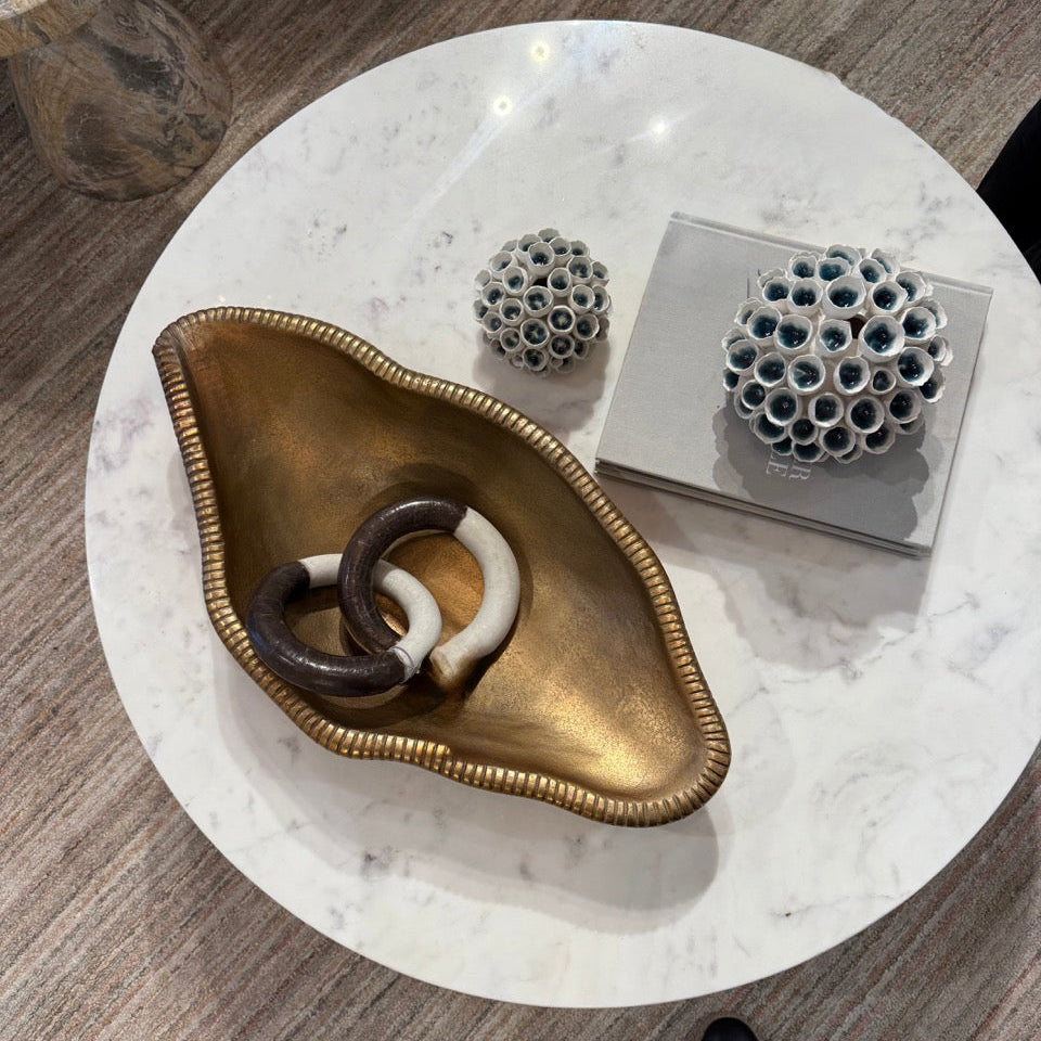 Round marble coffee table with decorative items on a wooden floor