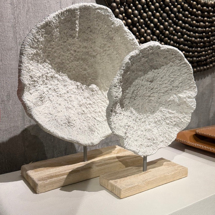 Decorative stone sculpture on a wooden stand with a textured wall and mirror in the background.