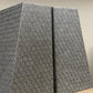 Two textured gray boxes on a beige surface