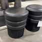 Black cushioned stools on a concrete floor with a blurred background