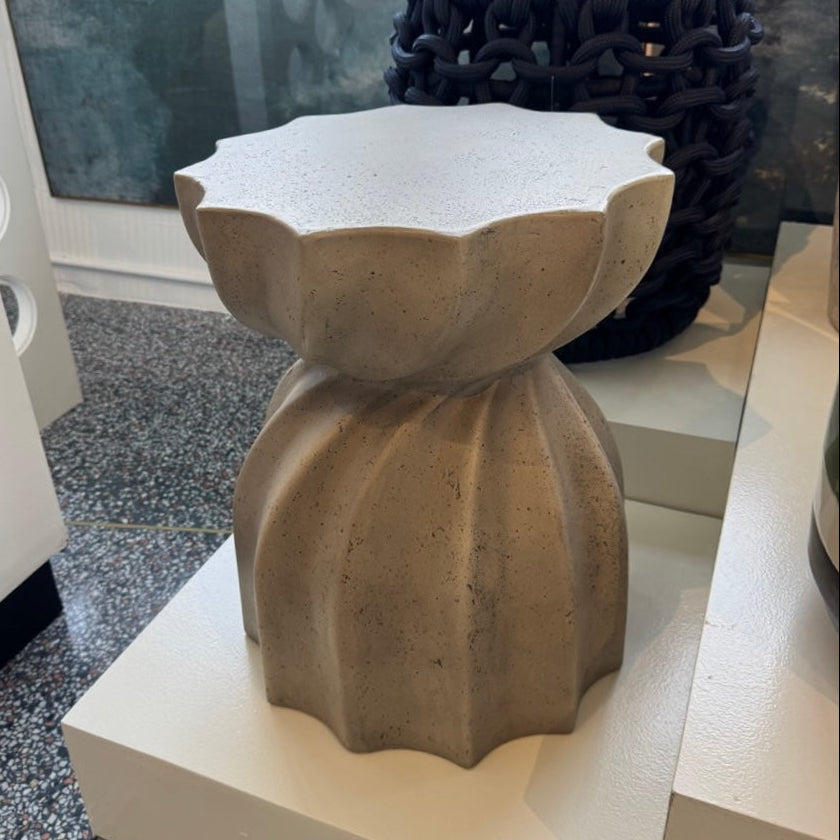 Decorative stone stool on a white surface with a textured background
