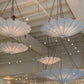 Decorative chandeliers hanging from a ceiling in a showroom setting.