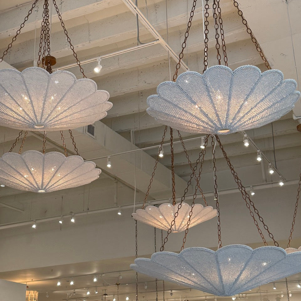 Decorative chandeliers hanging from a ceiling in a showroom setting.