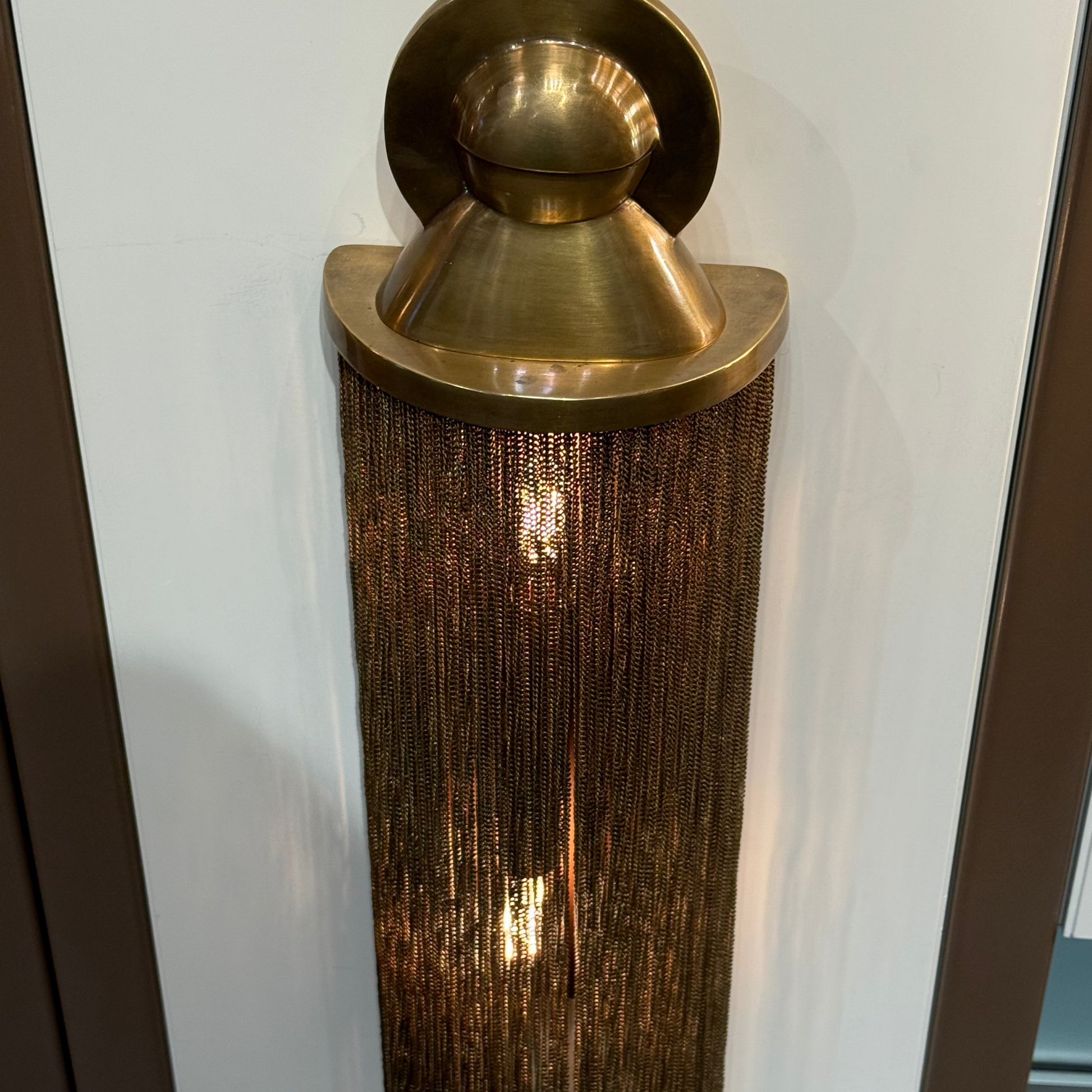 Brass wall sconce with textured shade on a white wall