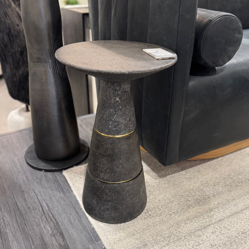 Dark gray side table with gold accents in a room with furniture