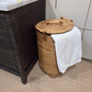 Wicker laundry basket with a white towel next to a dark wooden cabinet in a bathroom.