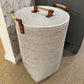Woven laundry basket with wooden handles in a room setting