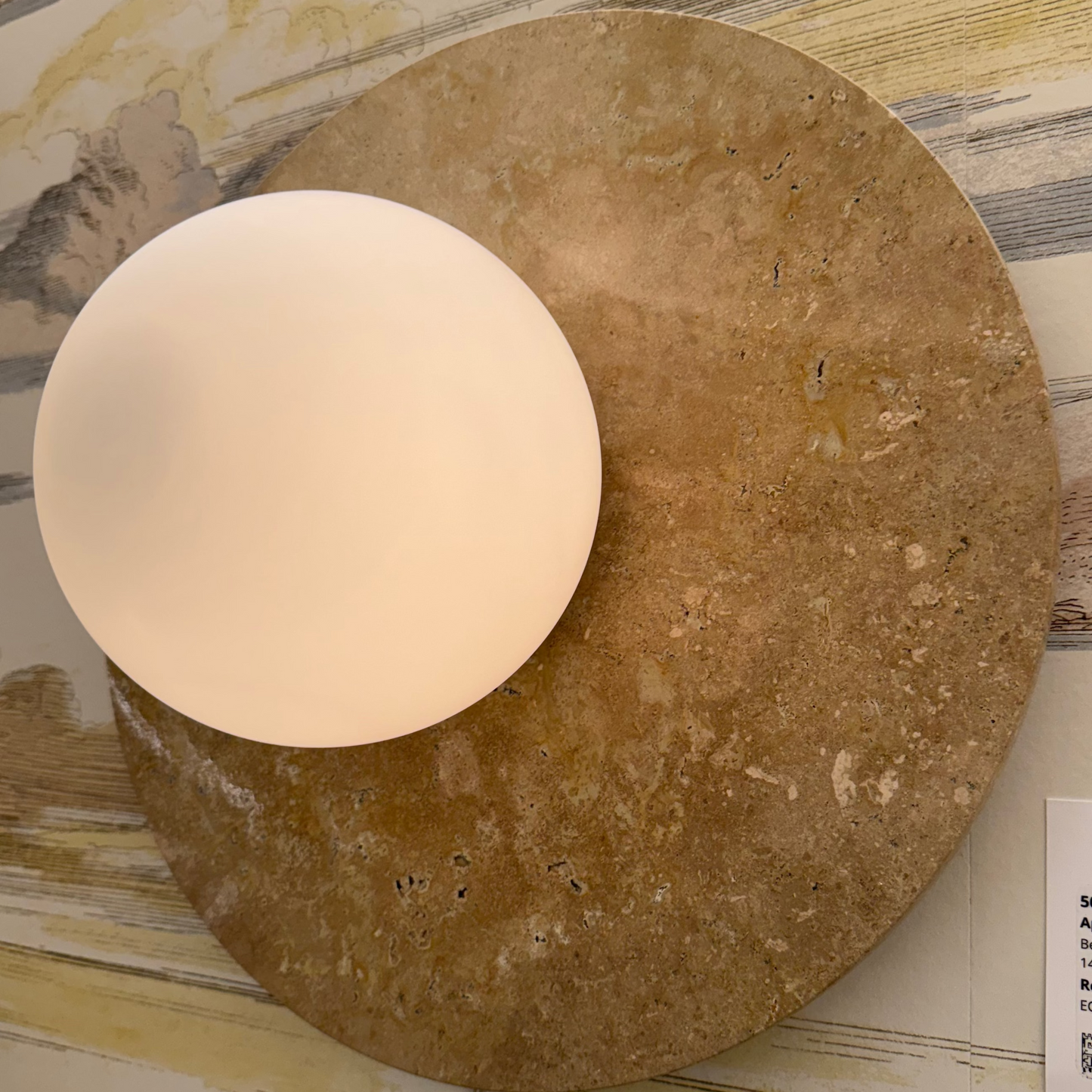 Round wall light fixture with a textured brown base on a decorative wall.