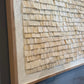 Close-up of a textured wall panel with wooden shingles on a dark background
