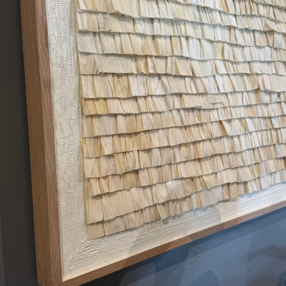 Close-up of a textured wall panel with wooden shingles on a dark background
