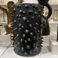 Black ceramic pitcher with spiky texture in a showroom setting