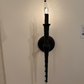 Decorative wall sconce with a long arm on a plain wall.