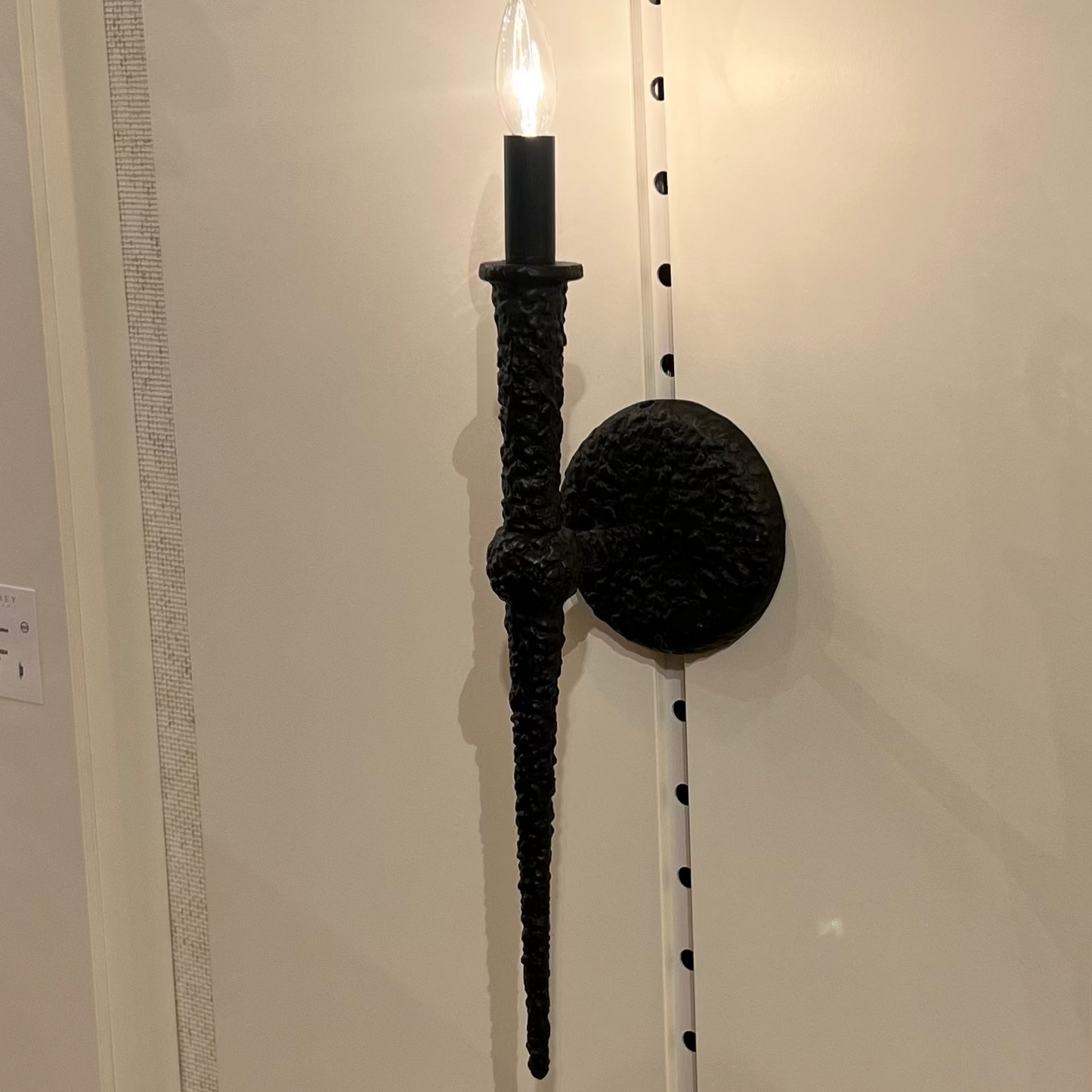 Wall-mounted candle holder with a black finish on a white wall.