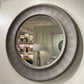 Round wall mirror with metallic frame on a white wall