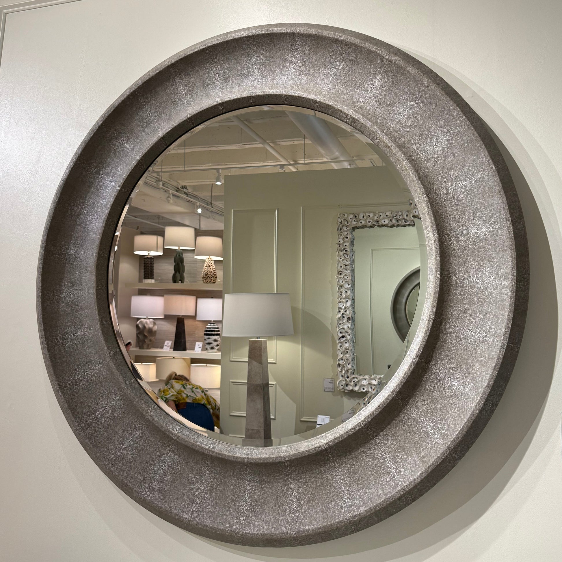 Round wall mirror with metallic frame on a white wall
