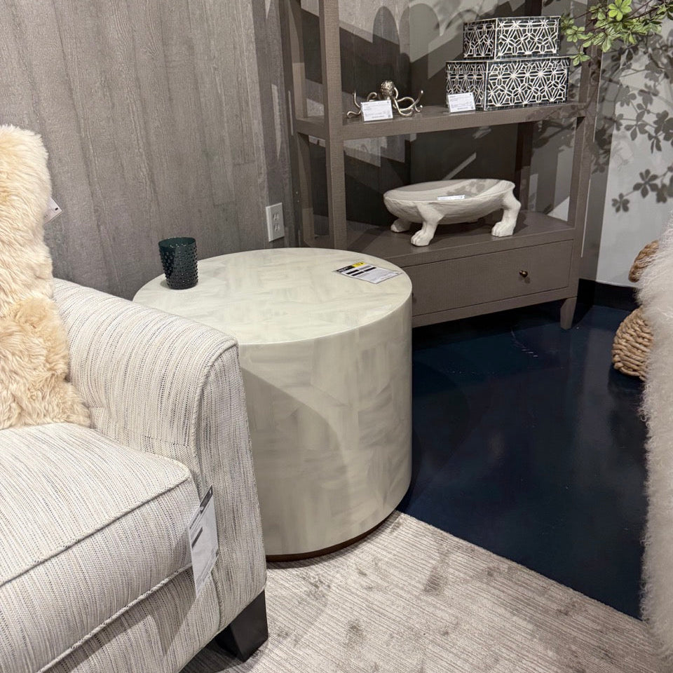 Living room with a round coffee table, armchair, and decorative shelf.